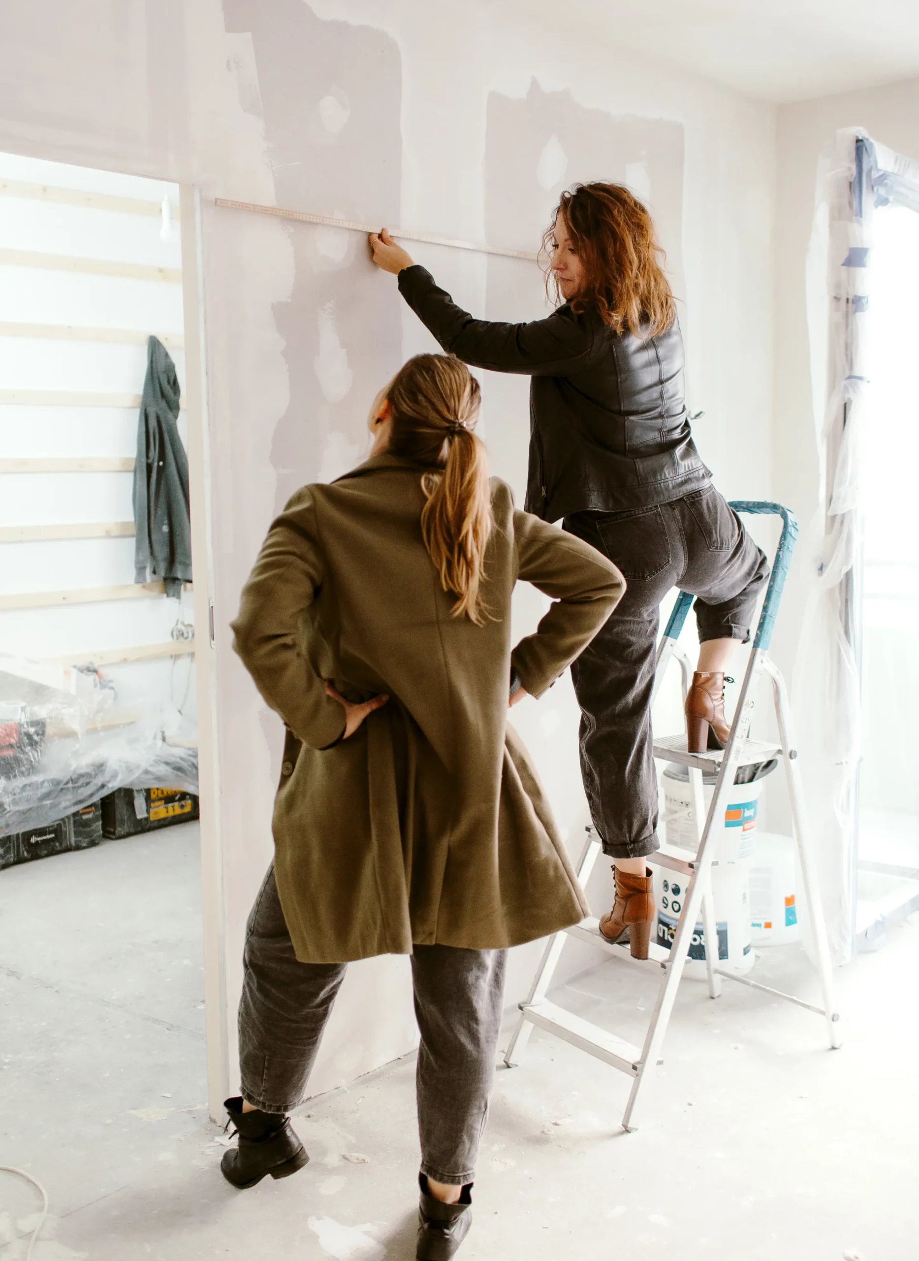 projektantki sprawdzają wymiary ścian na budowie, jest to jeden z elementów początkowych prac projektanta, wykonanie dokładnej inwentaryzacji rozpoczyna proces projektowania, obmiary są niezbędne do wykonania projektu. umożliwia to wykonanie rzetelnego projektu oraz ułatwia późniejsze prace wykończeniowe